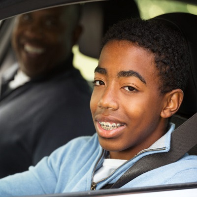 teen boy driving with parent
