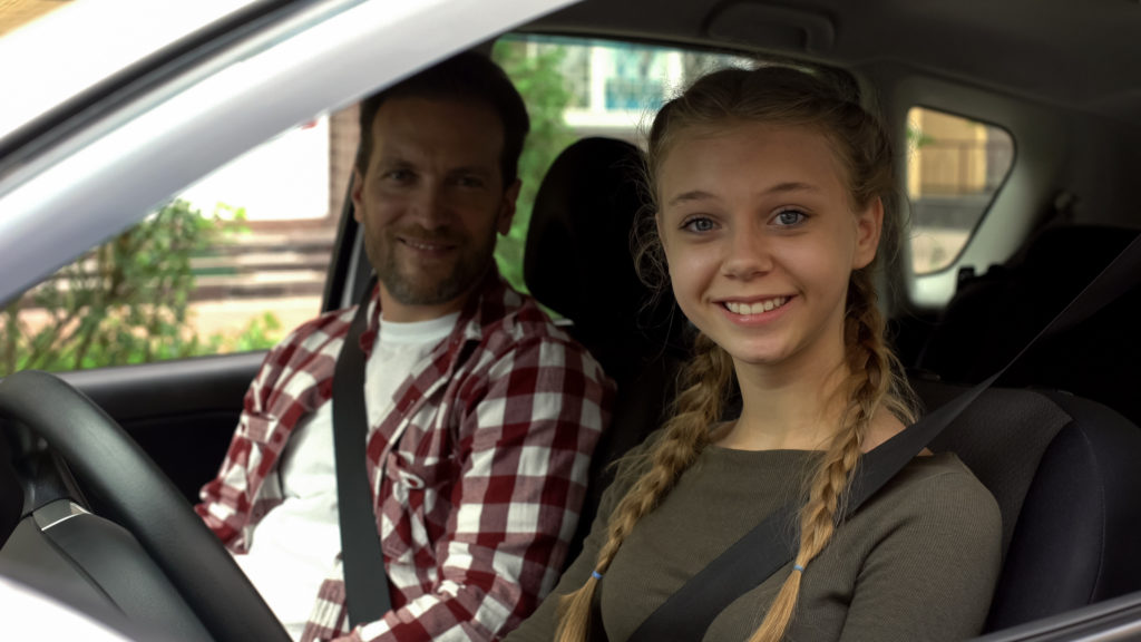Teen girl driving with her dad in the passenger seat